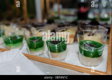 A close-up of a serving tray showcasing four green layered dessert cups at a catering buffet, suggesting a vibrant, elegant event with a focus on food Stock Photo