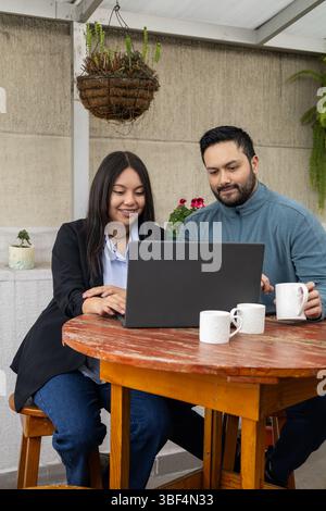 Coworkers focus on the laptop screen, reviewing information with attention in a collaborative and professional setting. Stock Photo