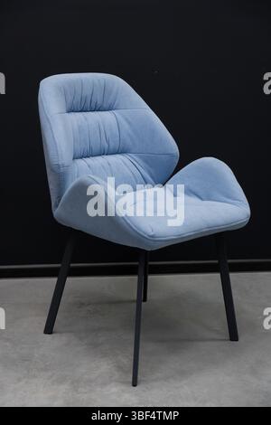 This image features a stylish, light blue upholstered accent chair with sleek black metal legs, set against a neutral gray floor, showcasing contempor Stock Photo