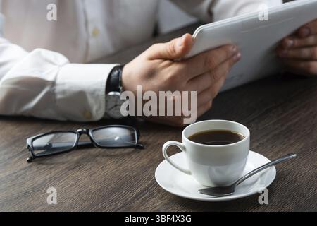 Business man working with tablet computer at office desk. Financial specialist working with online analytics. Businessman at workplace with cup of cof Stock Photo