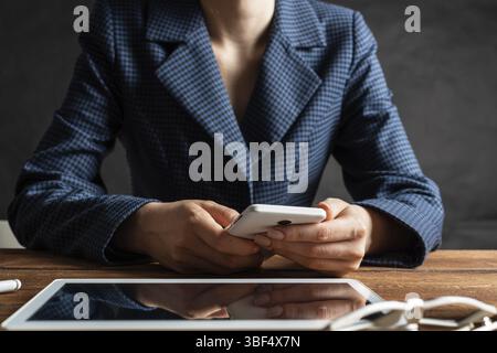 Businesswoman using mobile phone at desk. Close up woman hands and tablet computer. Mobile communication concept with chatting woman. Digital technolo Stock Photo