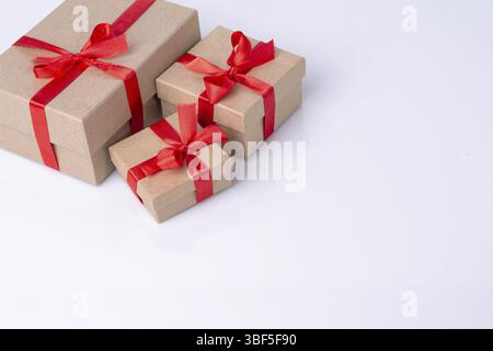 Craft boxes with gifts are tied with red ribbons, there is a place for text on the white glass Stock Photo