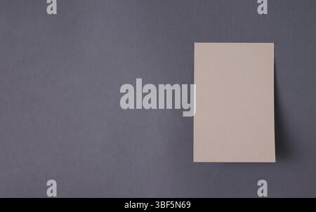 Blank paper sheet for announcement hanging on dark gray wall, mock-up, space for text Stock Photo
