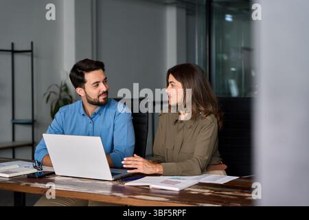 Happy professional business people working in office with laptop and talking. Stock Photo