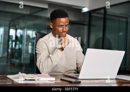 Busy African business man thinking on online investment working on laptop. Stock Photo