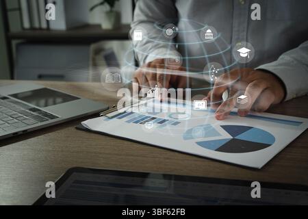 An online business coach person analyzing data charts and graphs paper with digital icons representing various educational and analytical concepts Stock Photo
