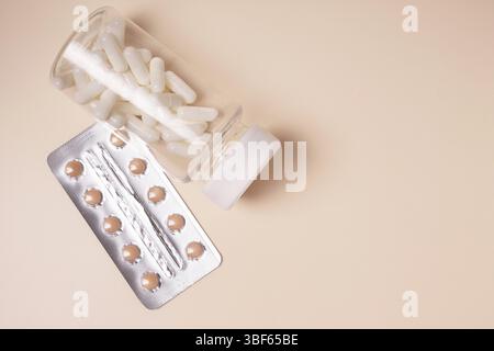 Bottle with white pills and blister with red pills on beige background, top view, copy space Stock Photo