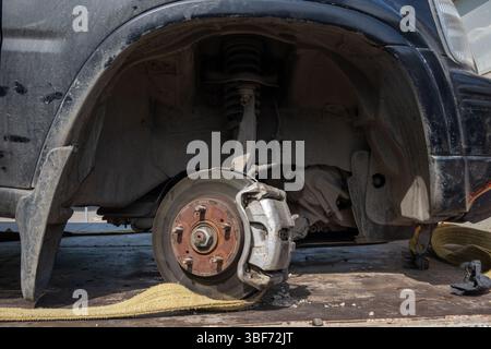 Exposed car brake disc and suspension system under a dusty wheel arch. Car maintenance or repair concept in sunlight Stock Photo