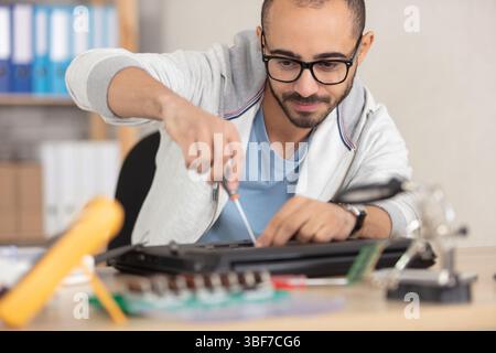 man repairing his laptop using a screwdriver Stock Photo