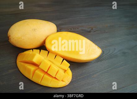 Mouthwatering Cut Fresh Ripe Mango with a Whole Fruit on Black wooden Background Stock Photo