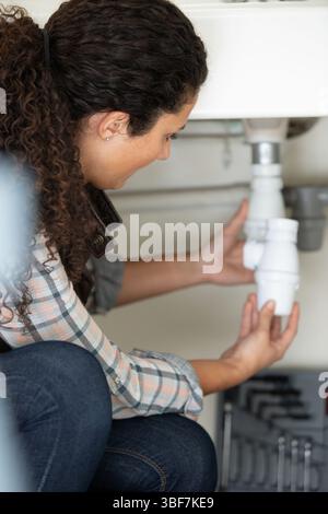 young female plumber fixing a bathroom sink Stock Photo