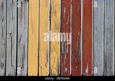 Weathered multi-colored wooden fence panels showing a blend of vibrant and rustic painted hues, featuring distinctive character and charm, perfect for Stock Photo