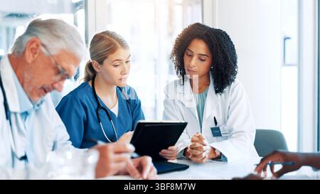 Tablet, meeting and team of doctors in hospital boardroom with medical report for treatment planning. Digital technology, research and group of Stock Photo