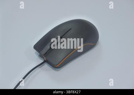 a black wired mouse with orange stripes made of plastic, with a gray background as an interactive controller on the computer Stock Photo