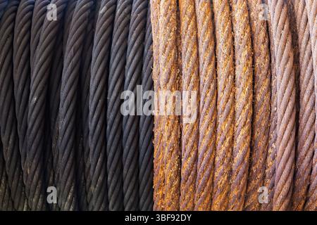 A rusty steel cable wound on a winch next to a greased new cable. Stock Photo