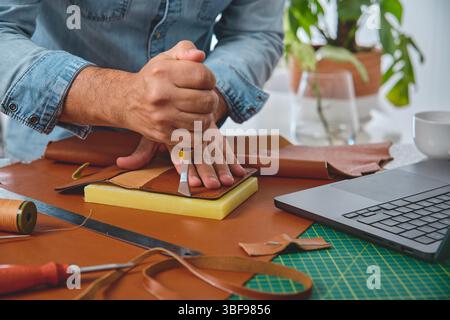 Shoemaker cutting leather in a traditional workshop using a cutter Stock Photo