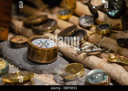 Assorted antique brass compasses displayed on textured wooden surface, evoking a nautical adventure mood and classic maritime exploration themes. Stock Photo