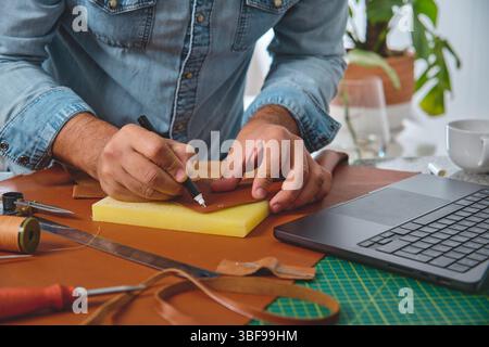 Craftsman meticulously marking leather for a new bag, showcasing traditional craftsmanship in a modern workspace Stock Photo