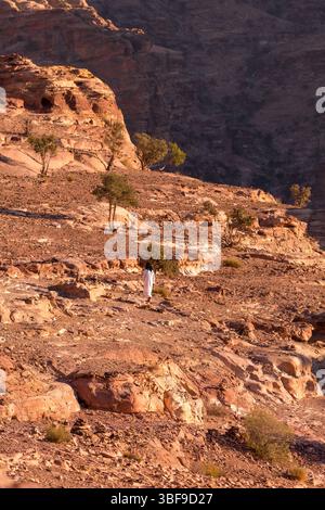 Petra, Jordan - November 3, 2022: Bedouin man walking in sandstone canyon, rocks formations landscape Stock Photo