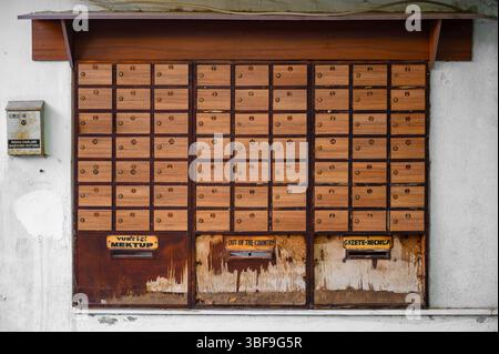 Vintage wooden mailboxes on a weathered wall in Turkey, labeled for local, international letters, and newspapers—urban retro detail. Stock Photo