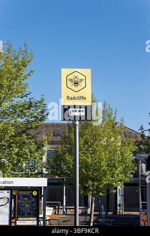 Bee network bus station sign with trees and bus station in background,  bright sunshine and blue sky in Radcliffe greater manchester uk Stock Photo