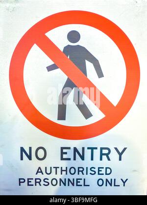 Photograph of an old and dirty plastic No Entry and Authorised Personnel Only sign on the wall of an industrial building workshop. Stock Photo