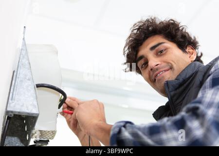 smiling handsome electrician repairing electrical box Stock Photo