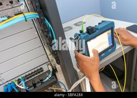 A technician uses specialized cable testing equipment to assess network performance and maintain connectivity in a data center environment. Stock Photo