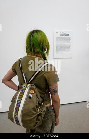 Unconventionally dressed young woman studies signage at the Museum of Modern Art exhibit, 2025, New York City, United States Stock Photo