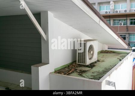 An air conditioning unit is positioned on a rooftop, showcasing its importance in climate control. The area shows signs of neglect and debris accumula Stock Photo
