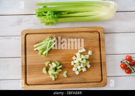 Celery stalks sliced in multiple ways on a wooden board, top view, for meal prep. Healthy cooking Stock Photo