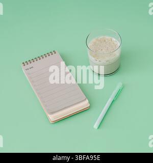 To do list in spiral notepad with iced matcha latte. Trendy pastel green background. Stock Photo