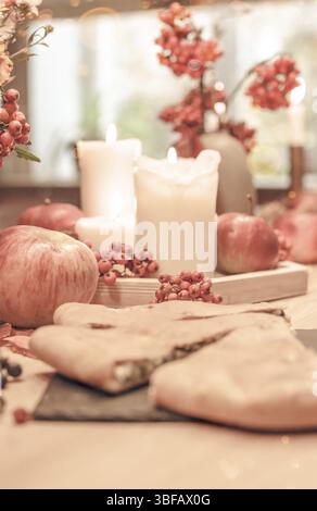 Autumn table decoration for Holiday Thanksgiving dinner. Cozy warm natural style with homemade pie, candles lights, red berries and apples Stock Photo
