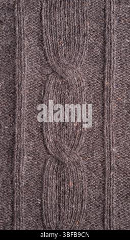 Brown knitted fabric with braids made of tweed yarn, texture background Stock Photo