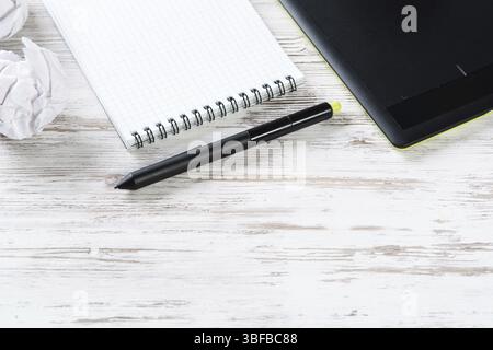 Still life of modern office workspace with copy space. Flat lay composition with graphic tablet and spiral notepad on wooden surface. Time management Stock Photo