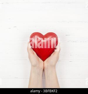 Creative Valentine Day romantic composition flat lay top view love holiday celebration with red heart in hands white wooden background copy space Temp Stock Photo