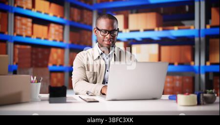 Delivery Worker Scanning Laptop For Online Merchandise Inventory In Warehouse Stock Photo