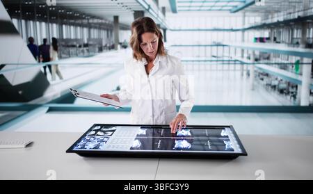 Female Radiologist Uses Computer To View MRI Scans In Hospital Stock Photo