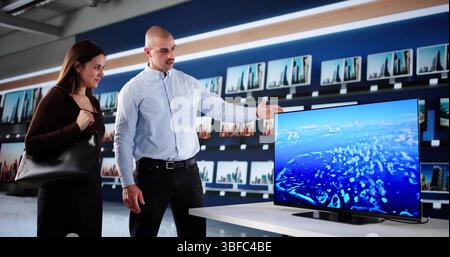 Man In Smart TV Store Showroom Advising Couple On Appliances Stock Photo