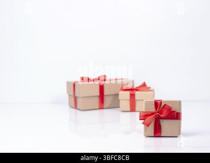 Craft gift boxes are tied with red ribbons, there is a place for text on the white glass, selective focus Stock Photo
