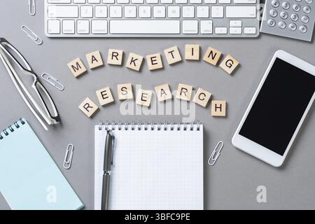 Marketing research concept with letters on cubes. Still life of office workspace with supplies. Flat lay grey surface with pc keyboard and notebook. N Stock Photo