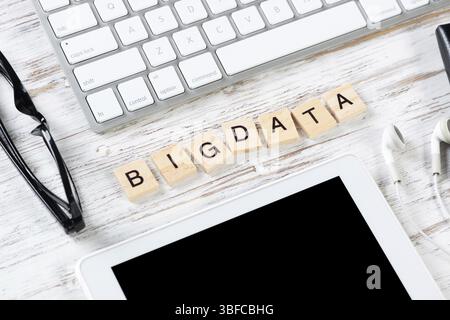 Big data analytics concept with letters on cubes. Still life of workplace with supplies. Flat lay vintage white wooden desk with computer keyboard and Stock Photo