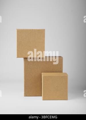 Three square cardboard boxes stand on white background, mockup Stock Photo