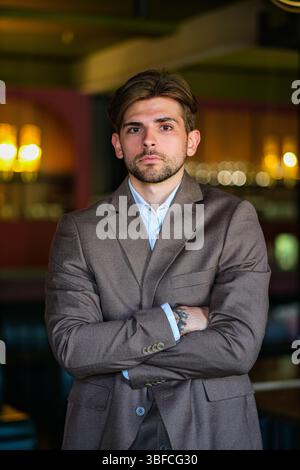 moscow, russia, 22.05.2025 A man in a brown suit is standing in a bar. He is wearing a blue shirt and has tattoos on his arm Stock Photo