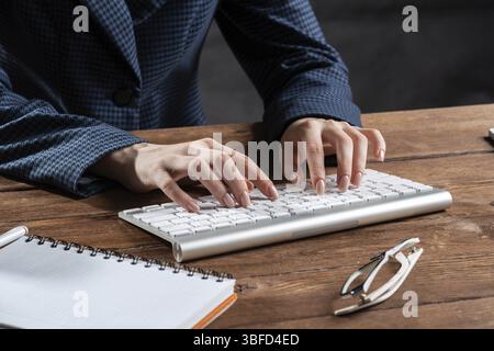 Close up woman hands lying on laptop keyboard. Business lady working with computer at wooden desk. Financial specialist working at workplace in office Stock Photo