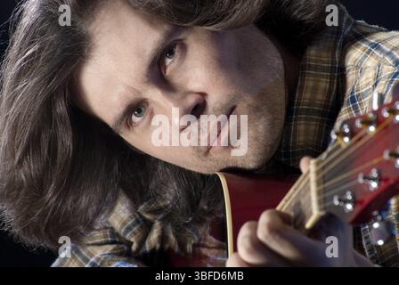 Guitarist. Closeup shoot of man with long hair plaing on a acoustic guitar Stock Photo