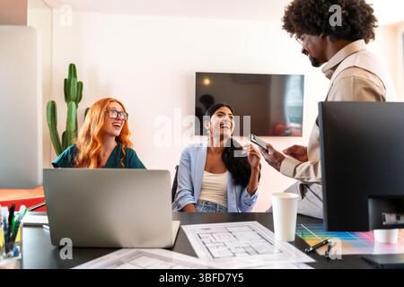 Multiethnic small group of businesspeople meeting in a coworking corporate company office - Young coworkers colleagues working together in a creative Stock Photo