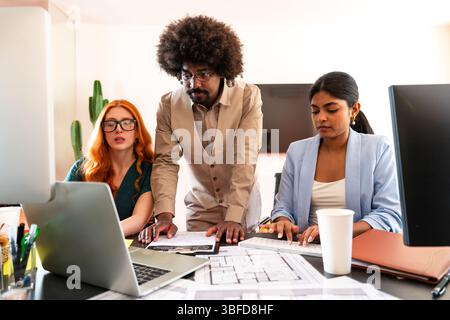 Multiethnic small group of businesspeople meeting in a coworking corporate company office - Young coworkers colleagues working together in a creative Stock Photo