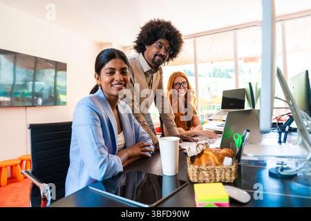 Multiethnic small group of businesspeople meeting in a coworking corporate company office - Young coworkers colleagues working together in a creative Stock Photo