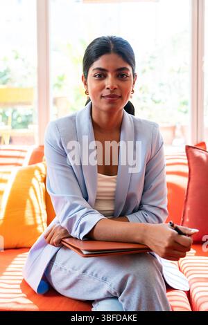 Beautiful indian business woman working in a coworking corporate company office - Young female wearing business casual clothing works in a creative st Stock Photo